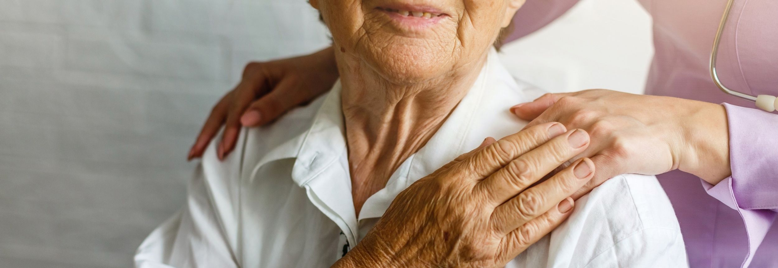 Ärztin legt Hand auf Schulter einer älteren Patientin